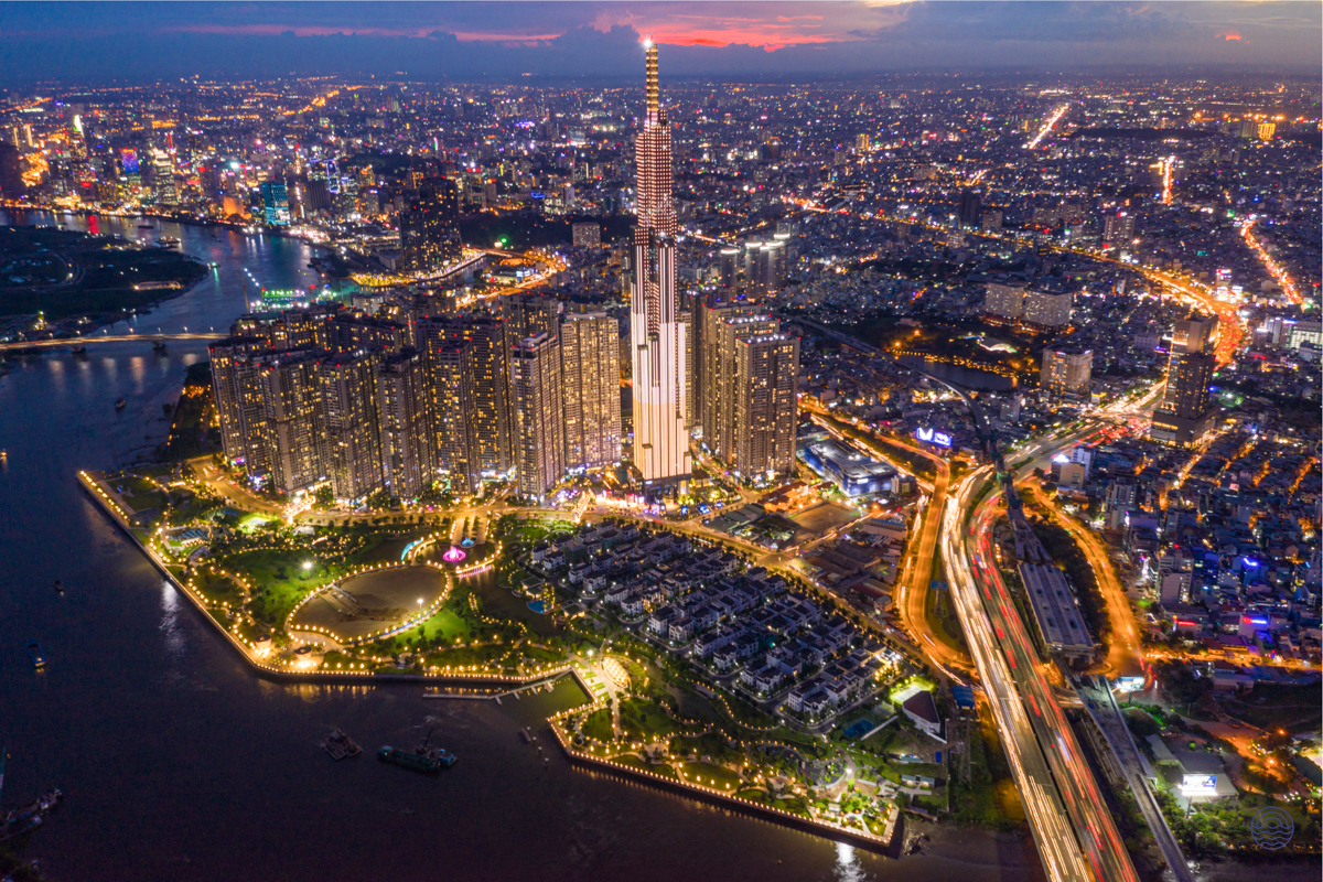 Ho Chi Minh City's dazzling nightscape with a prominent skyscraper, glowing park, and busy river.