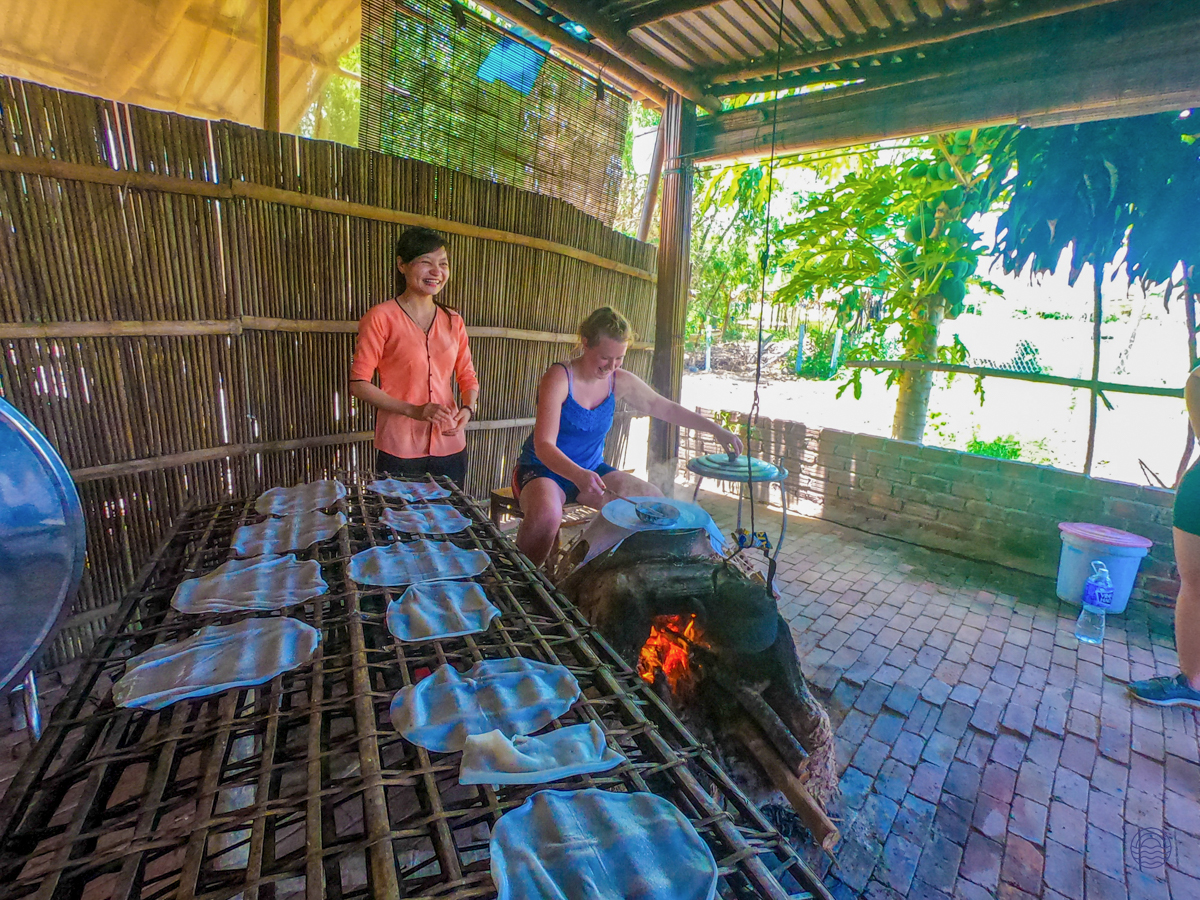 A woman cooks traditional Vietnamese food over an open fire with a local guide in Hoi An.