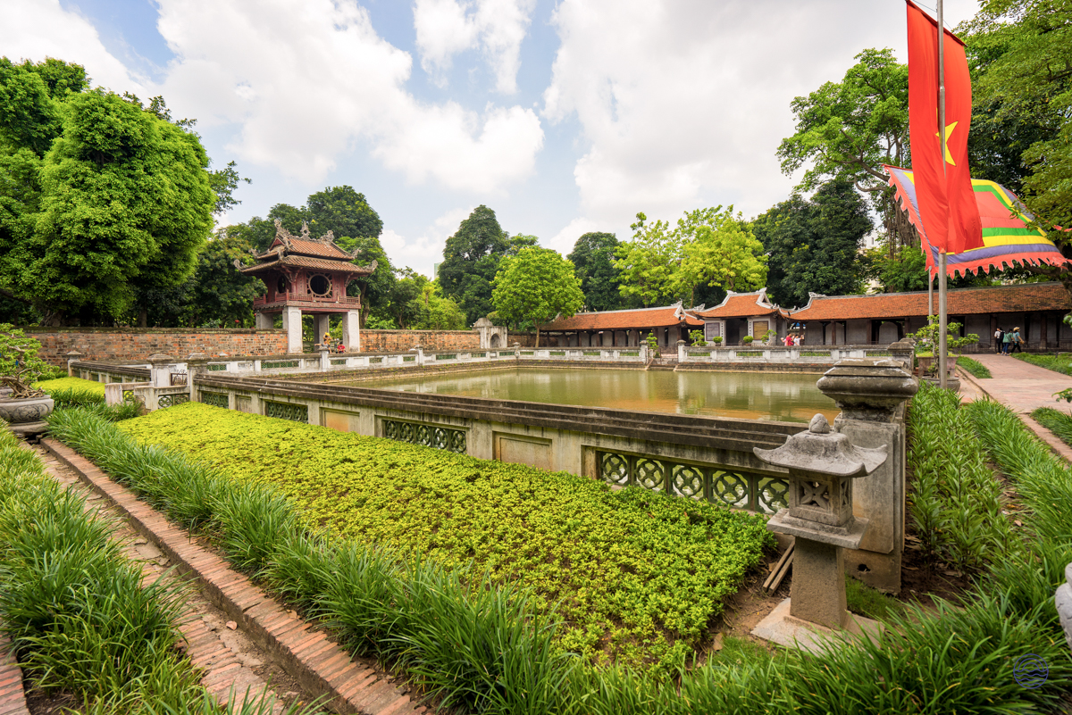 Historic Vietnamese temple grounds in Hue feature a serene pond, lush greenery, and traditional buildings.