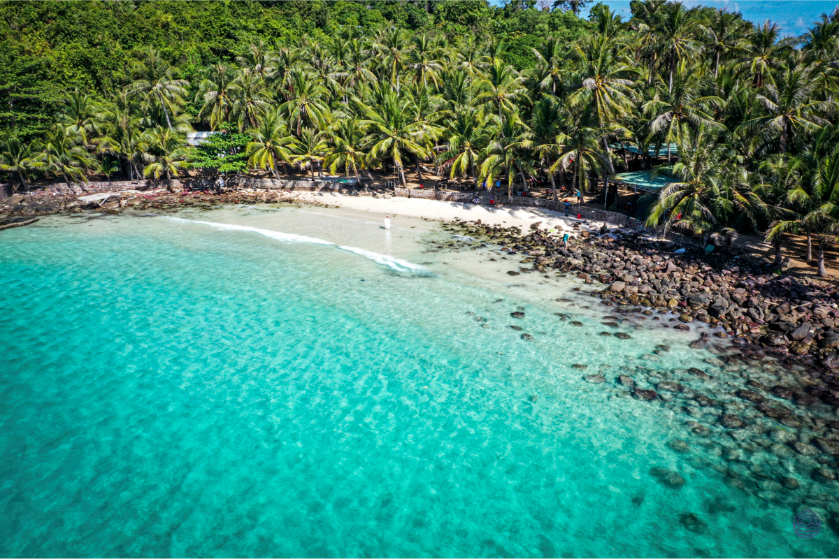 Stunning aerial view of a secluded Phu Quoc beach with clear turquoise water and dense palm jungle.