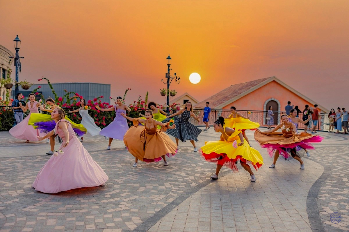 Dancers in vibrant dresses perform outdoors at sunset in Phu Quoc's charming Sunset Town.
