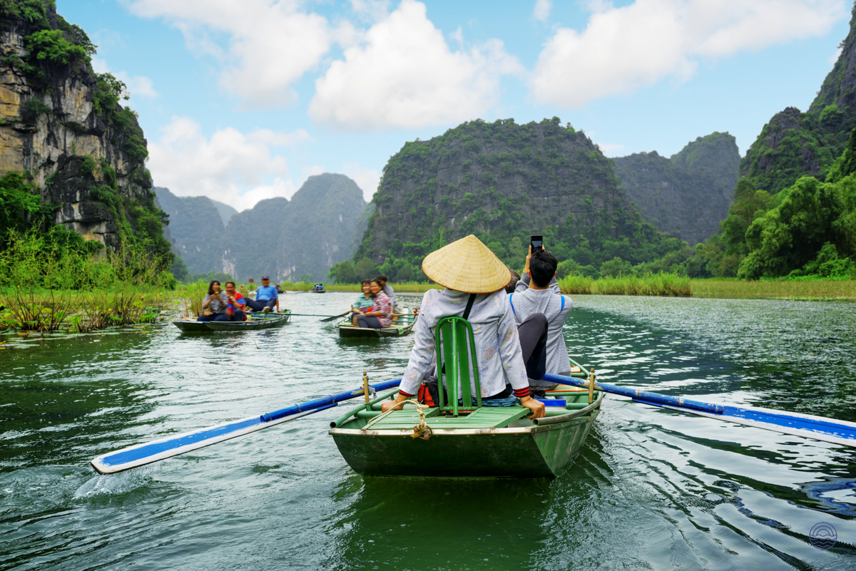 Tourists enjoy a serene sampan boat ride through the stunning karst landscape of Tam Coc, Vietnam.