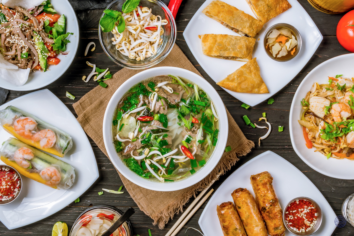 An inviting tabletop filled with a variety of authentic Vietnamese cuisine, featuring pho, spring rolls, and noodles.