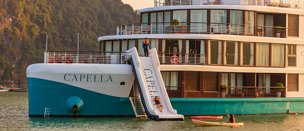 Guests enjoy a thrilling water slide and kayaking from the Capella cruise ship in scenic Halong Bay.