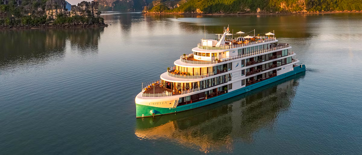 A luxurious cruise ship with multiple decks and balconies sails through scenic Halong Bay.