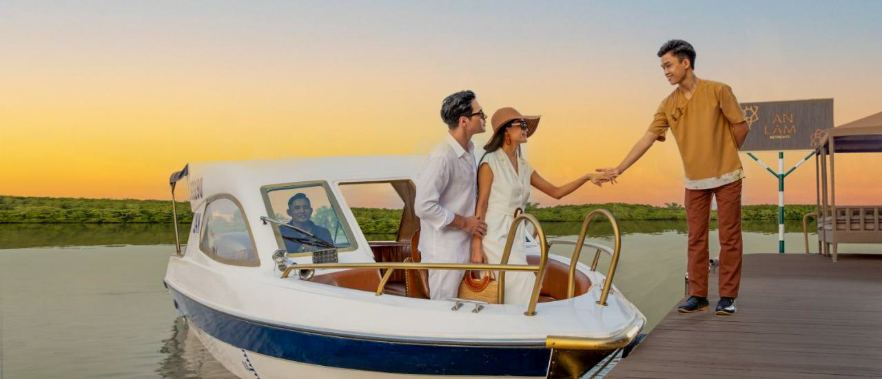 A couple disembarking a boat at sunset in Ho Chi Minh City, assisted by a staff member.