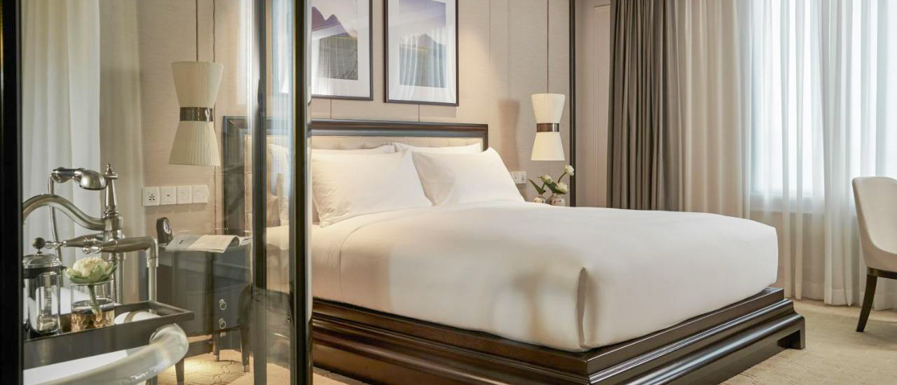 A sophisticated hotel bedroom with a plush bed, sleek furniture, and soft lighting in Ho Chi Minh City.