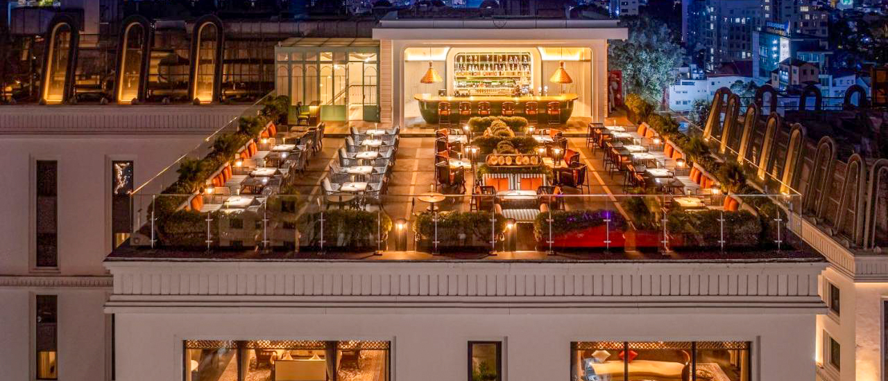 Luxurious rooftop bar and restaurant illuminated at night, overlooking Ho Chi Minh City.