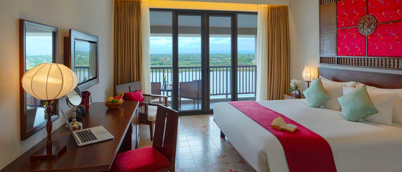 Elegant hotel room in Hoi An with a comfortable bed, traditional accents, and a scenic river view.