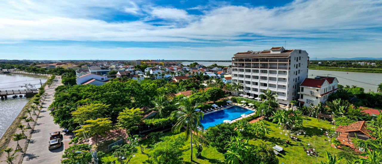 Aerial view of RiverTown Hoi An Resort & Spa, featuring a pool, lush gardens, and a river.