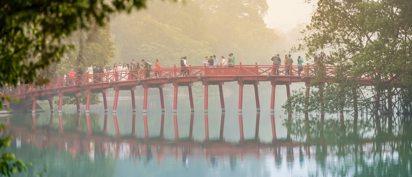 People stroll across the iconic red Huc Bridge over Hoan Kiem Lake in Hanoi.