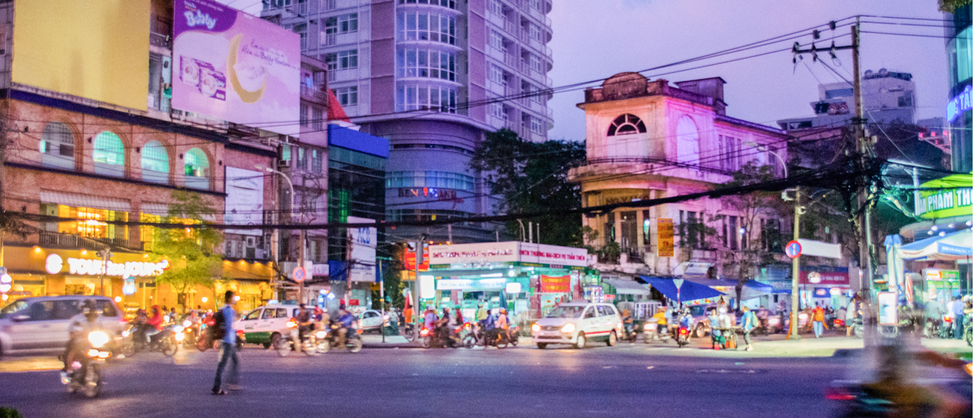 Vibrant Ho Chi Minh City street at night, filled with motorbikes, cars, and illuminated storefronts.