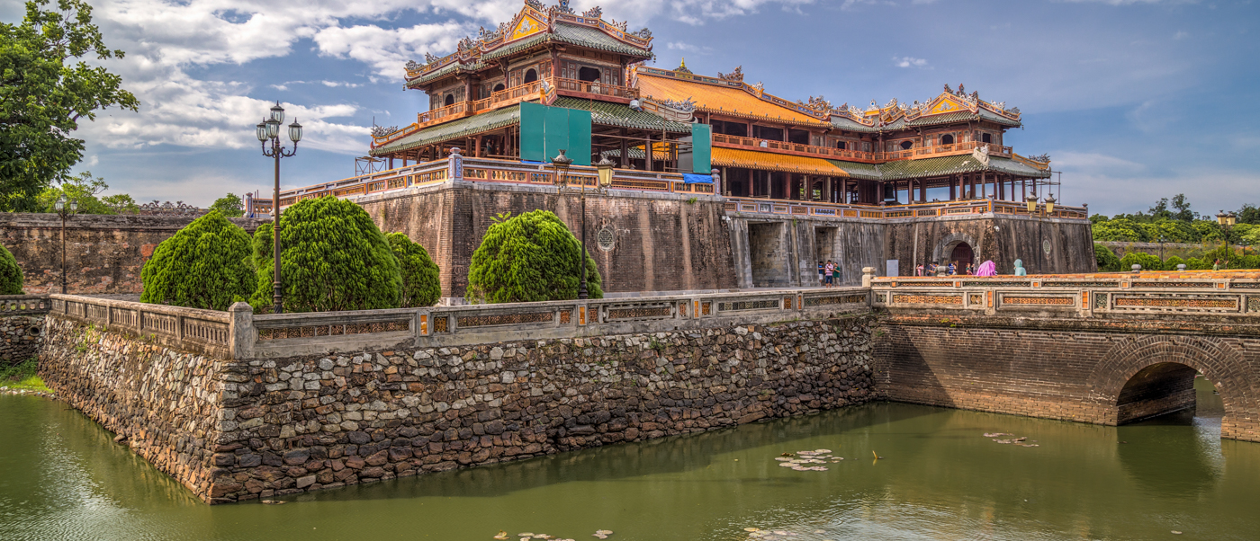The grand Imperial City of Hue, with ornate traditional architecture, a moat, and a stone bridge.