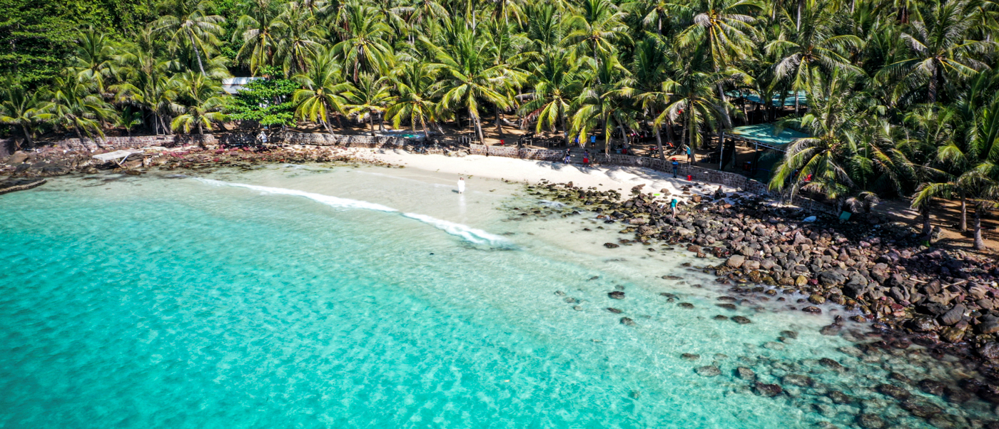 Aerial view of a pristine tropical beach with clear turquoise water and lush palm trees in Phu Quoc.