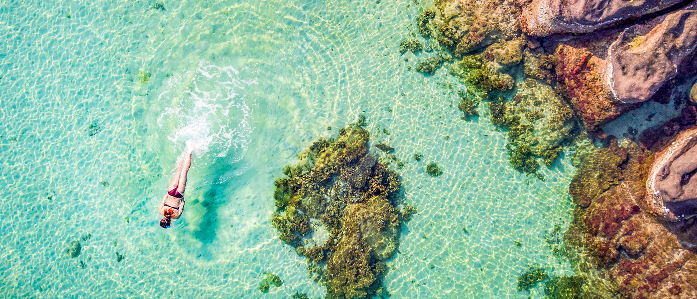 A person enjoys snorkeling in the pristine, clear turquoise waters near rocky formations in Phu Quoc.