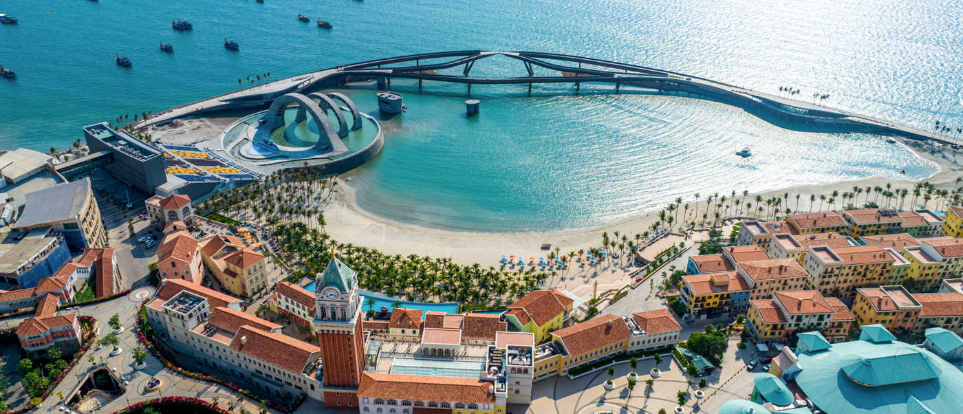 Phu Quoc's vibrant coastal resort town, featuring a sandy beach, turquoise bay, and a long pier.