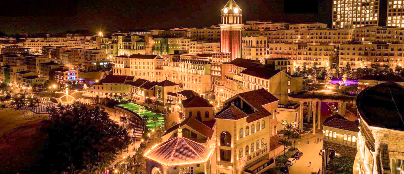 Vibrant night view of Phu Quoc's Sunset Town, showcasing illuminated Mediterranean-style buildings and a glowing canal.