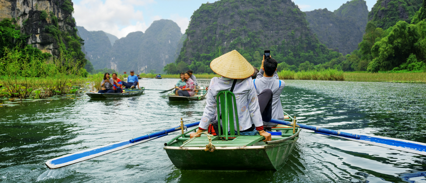 Tourists enjoy a serene sampan boat ride through the scenic waterways of Tam Coc, Vietnam.
